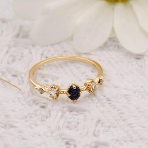 Détail d'une bague dorée avec pierre de sable bleu et topaze sur un tissu en dentelle