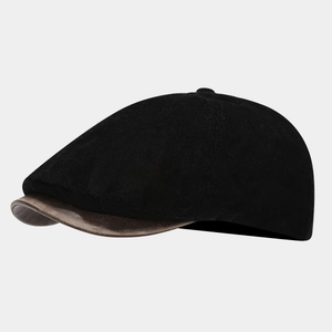 Detailed side view of black corduroy beret cap with brown faux leather visor