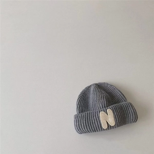 Close-up of gray knit beanie featuring a ribbed texture and cream 'N' letter patch