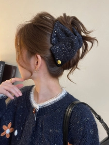Deep blue tweed bow hair claw clip with golden emblem and sequins on elegant updo