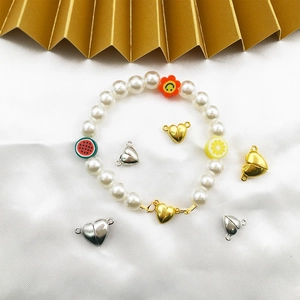 DIY charm bracelet with white pearls and heart-shaped magnetic clasps on white silk