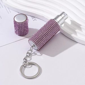 Pink rhinestone portable perfume spray bottle with silver keychain on white background