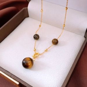 Macro shot of tiger eye stone pendant and beaded gold chain necklace in a gift box