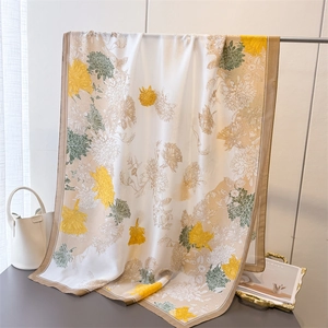 Detail view of floral silk scarf showing elegant yellow chrysanthemum prints and silk texture