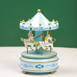 Detailed view of light blue carousel music box with gold trim on a white textured surface