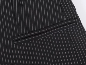 Macro shot of vertical striped fabric texture and stitched pocket detail on black blazer