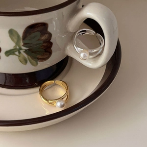 Detail of silver and gold pearl rings on a ceramic cup with S925 hallmark