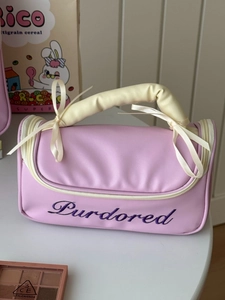 Close-up of pink ballet-style makeup bag featuring cream quilted handle and bow detail