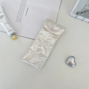 Detailed view of cream PU bow quilted sunglass pouch with soft cotton padding and heart clasp