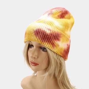 Detailed close-up of yellow and red tie-dye knit beanie with thick core-spun yarn texture
