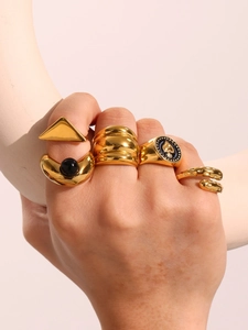 Close-up of five gold rings set featuring black enamel heart and geometric textures