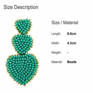 Size detail showing green beaded heart earrings, 8.6cm length and 4.3cm width dimensions