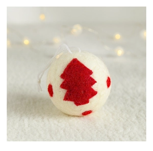 Detail of red wool felt Christmas ball ornament with white tree pattern and warm bokeh lights