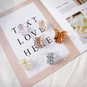 Flat lay of small acrylic butterfly hair claws in multiple colors on a magazine page