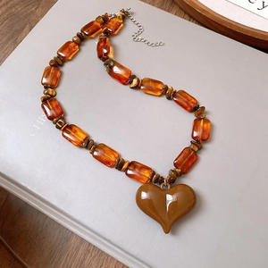 Macro view of vintage beaded necklace featuring brown resin beads and a heart pendant