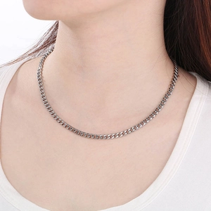 Close-up of silver stainless steel Cuban chain necklace worn by a model on white background