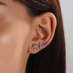 Close-up of small bear and colorful zircon stud earrings worn on model's earlobe