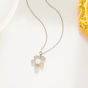 Macro shot of silver flower pendant with pearl center and pavé diamonds on white background