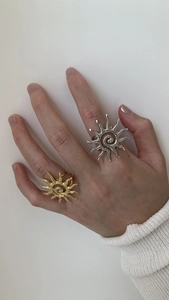 Detail of sun-shaped open rings in gold and silver finish with spiral center detail