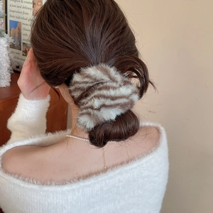 Dettaglio di un elastico per capelli a righe in finta pelliccia in uno chignon basso