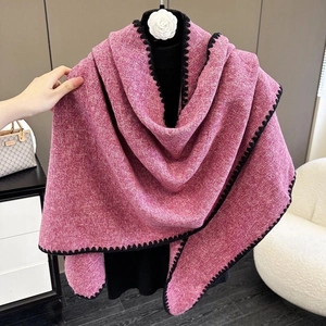 Detail of pink knitted triangle shawl featuring black embroidered edges and tweed texture