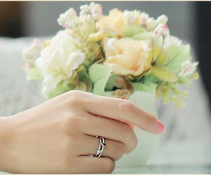 Close-up of sparkling hollow silver heart ring with small diamonds on model's finger
