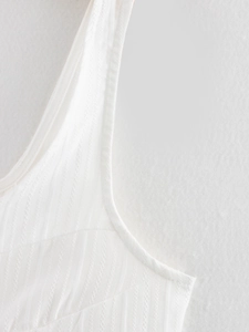 Close-up of white summer top featuring vertical ribbed knit texture and tie-front strap detail