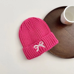 Cozy rose red knitted beanie for kids with a white bow accent, winter warm headwear