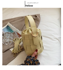Detail of light yellow woven bucket bag with drawstring closure and detachable strap