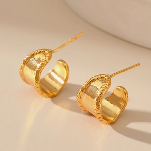Close-up of golden C-shaped hoop earrings with polished finish and rope texture edge