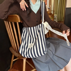 Detailed shot of blue and white striped canvas tote with delicate white lace ribbon decor