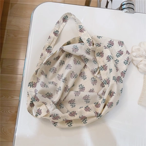 Close-up of vintage floral cotton shoulder bag with purple flower patterns on cream fabric