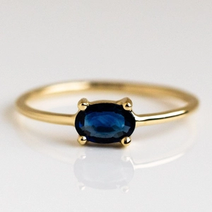 Detailed view of dark blue oval gemstone ring with golden brass four-prong setting