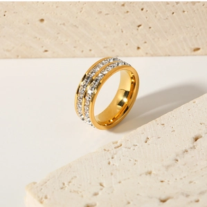 Close-up of golden double-row zircon ring on a textured stone base with luxury shine