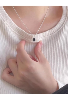 Close-up of a minimalist S925 sterling silver necklace with an oval black gemstone pendant
