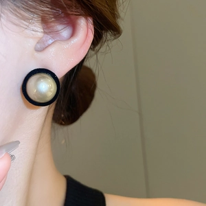 Close-up of elegant flocked velvet pearl stud earrings worn for a retro look