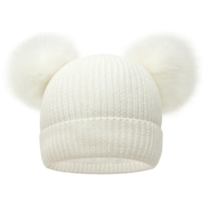 Close-up of white knitted beanie with double faux fur pom-poms and ribbed texture detail