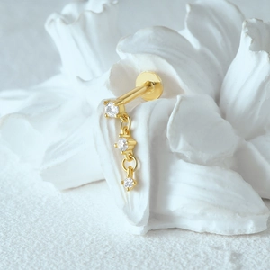 Detail of gold moon stud with three gradient zircons on a white floral background