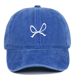 Close-up of white bow embroidery on washed navy cotton baseball cap with vintage texture