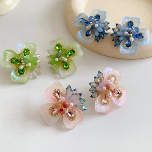 Vue détaillée de boucles d'oreilles fleurs en résine avec cristaux et perles