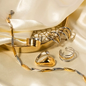 Minimalist gold and silver stainless steel rings and earrings on silk background