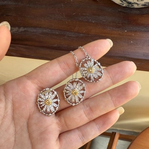 Detail of silver daisy jewelry set with white petals and yellow centers held by hand