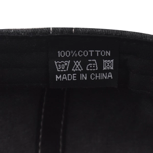 Detailed macro view of the 100% cotton wash care label inside a black baseball cap