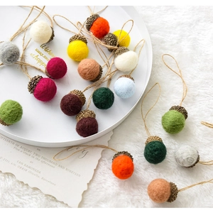 Colorful wool felt acorn ornaments with jute strings displayed on a white tray