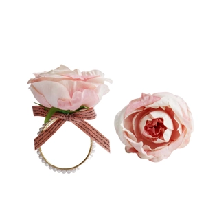Macro detail of silk rose napkin ring with gold band and pearl accents for wedding tables