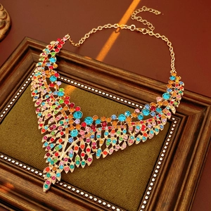 Macro view of vintage gold leaf necklace with colorful rhinestones on green fabric