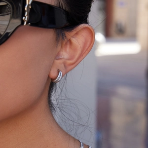 Close-up of minimalist silver stainless steel hoop earrings worn on a model's ear