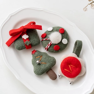 Handmade Christmas felt decorations with tree, wreath, and gift box designs on a white plate
