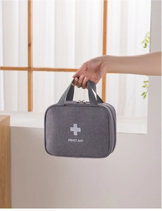 Portable gray first aid kit bag with top handle and white cross logo for travel use