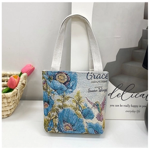 Close-up of hummingbird and floral embroidery on woven canvas tote bag detail